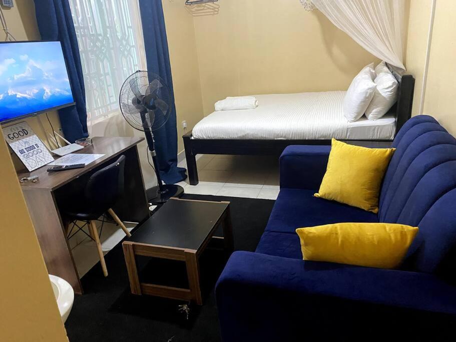 - un salon avec un canapé bleu et un lit dans l'établissement Pacho Studio-2, à Kisumu