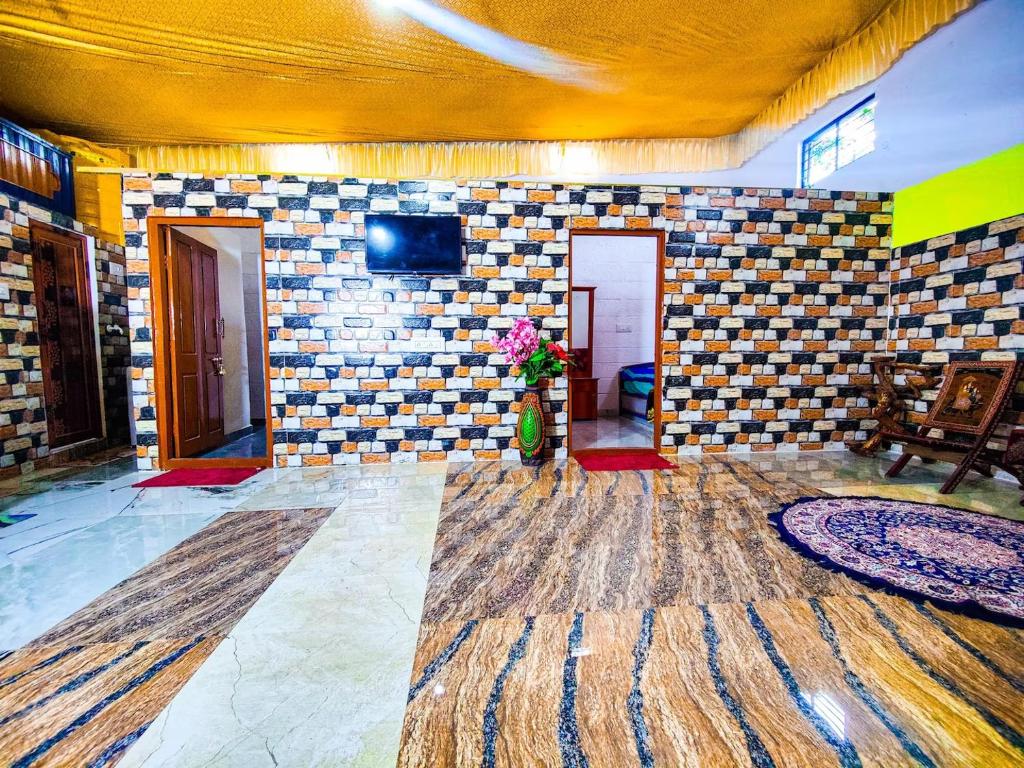 een kamer met een tegelmuur en een tv aan een muur bij Sahara Family Homestay in Mysore
