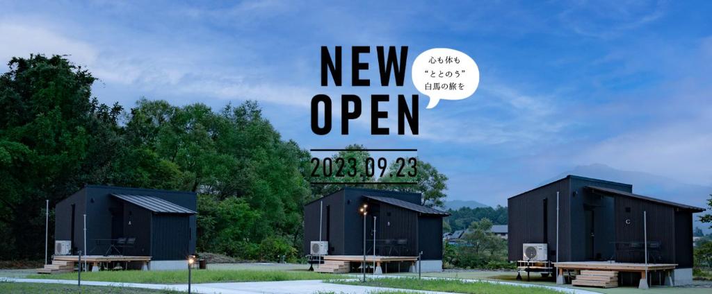 een groep zwarte gebouwen met een nieuw open bord bij Reposer Hakuba in Hakuba