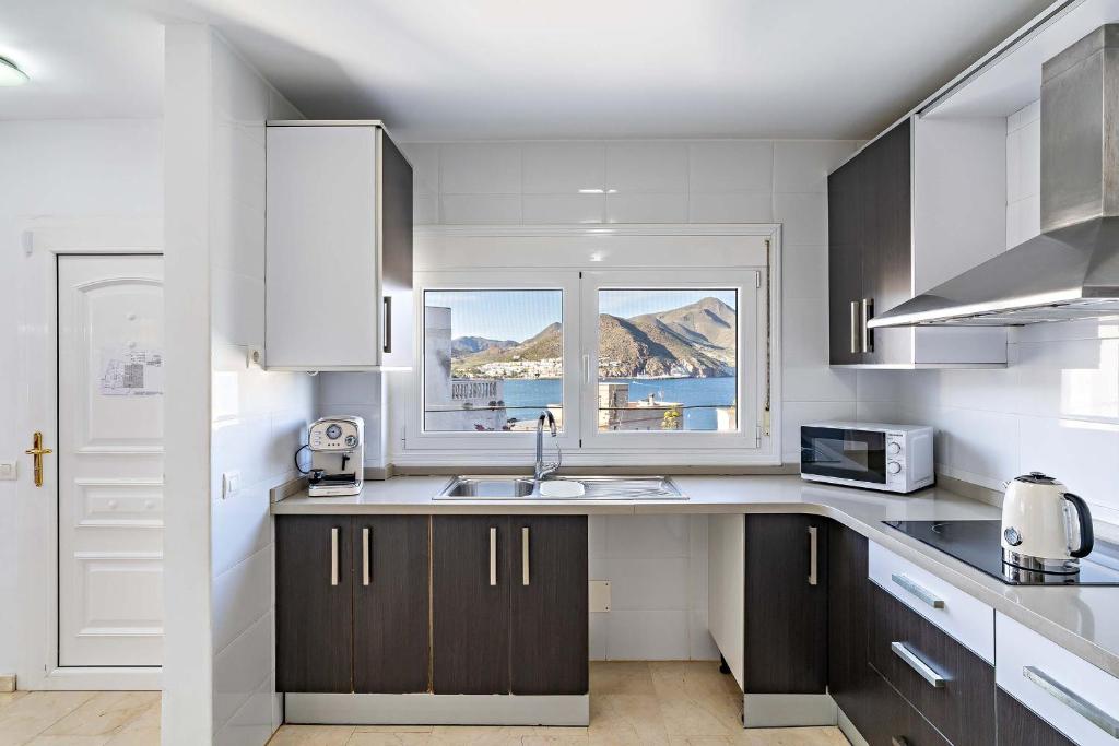 a kitchen with a sink and a window at Apartamentos Dulcemar Frente al Mar con zona SPA in San José