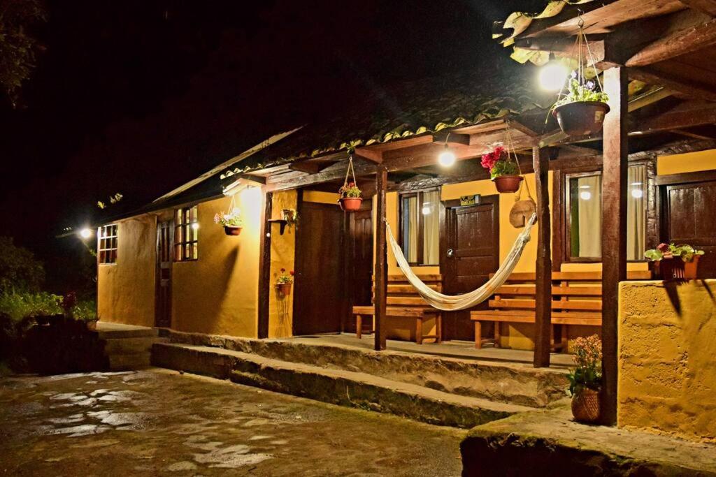 une maison avec une véranda éclairée la nuit dans l'établissement Hospedaje Dulce Piedad, à Ambato