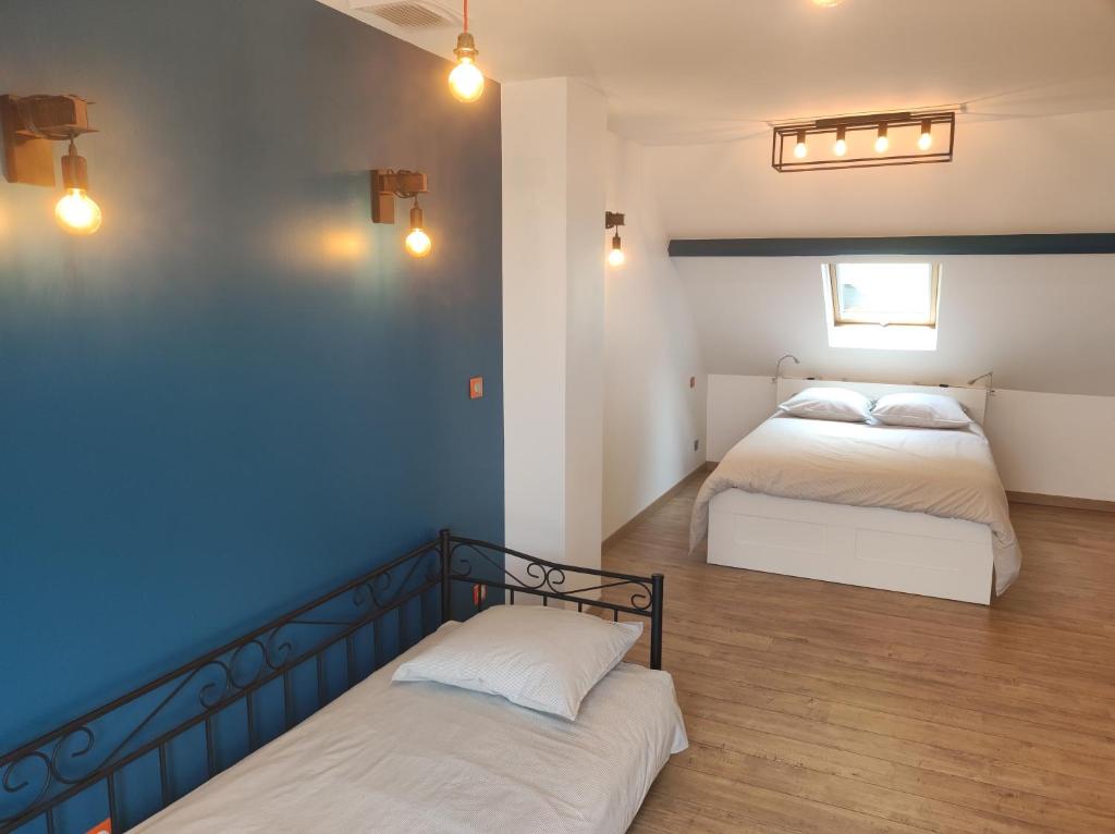 a bedroom with two beds and a blue wall at chez nanou&bibou in Auvers-sur-Oise