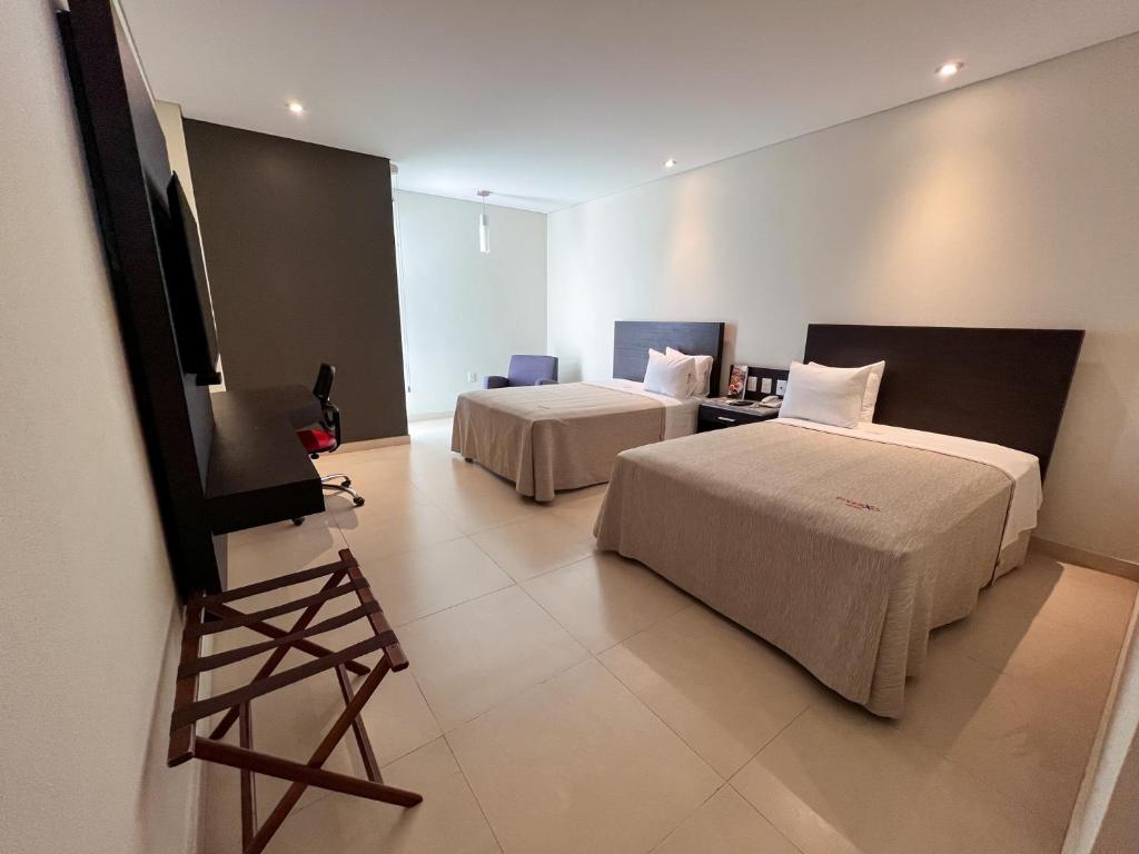 a hotel room with two beds and a television at Diverxo Hotel & Villas in Tuxtla Gutiérrez
