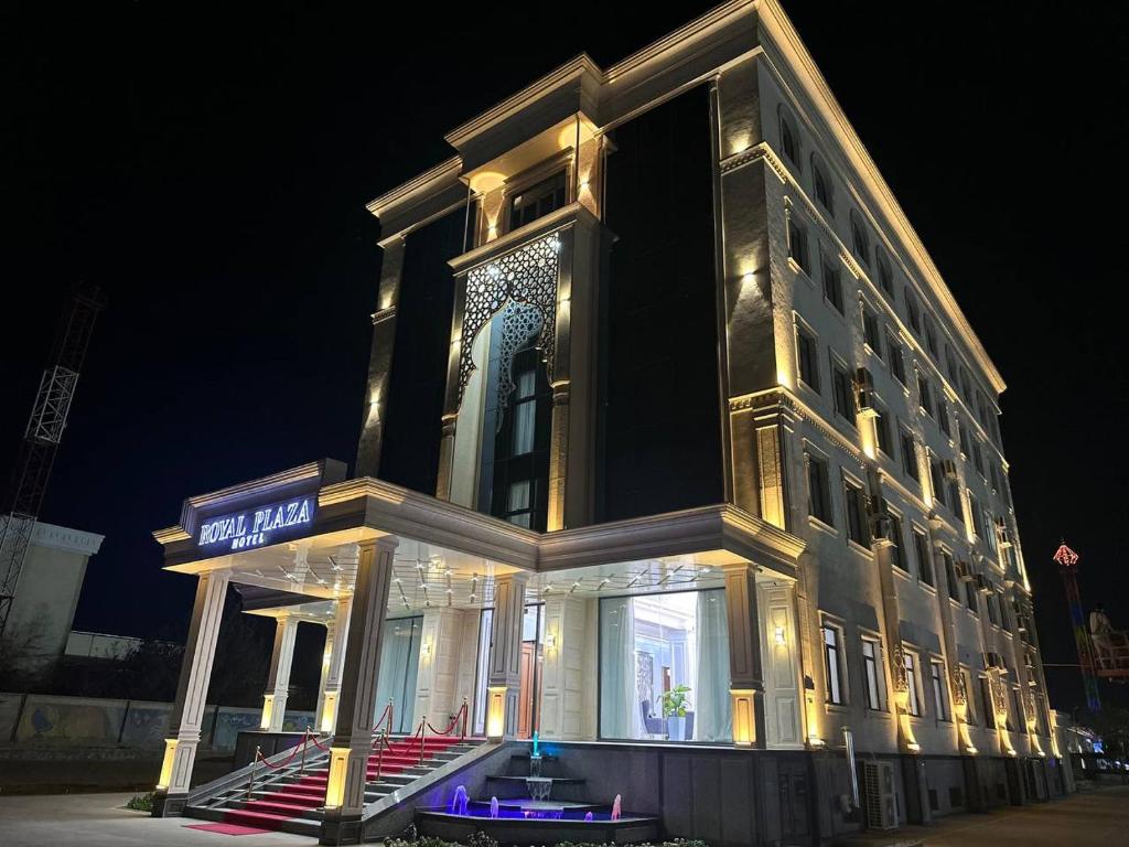 un grand bâtiment avec des lumières allumées la nuit dans l'établissement Royal Plaza, à Karshi