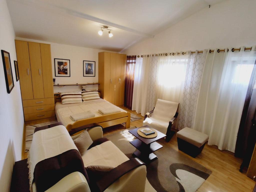1 dormitorio con cama, sofá y sillas en Apartman Orhideja en Novi Banovci