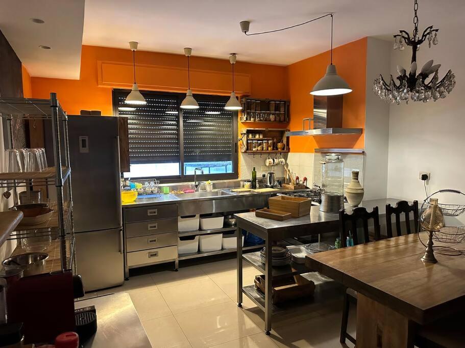 a large kitchen with orange walls and a table in it at Diplomatic apartment area in Ash Shumaysānī