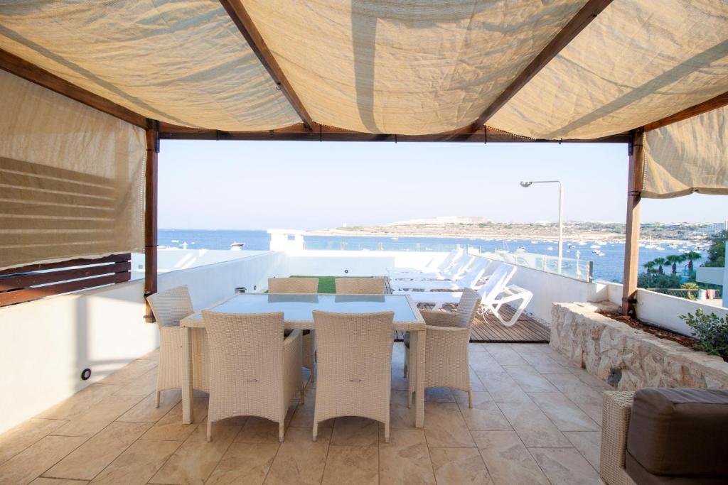 een eetkamer met een tafel en stoelen op een balkon bij VILLA JOSEPH in St Paul's Bay