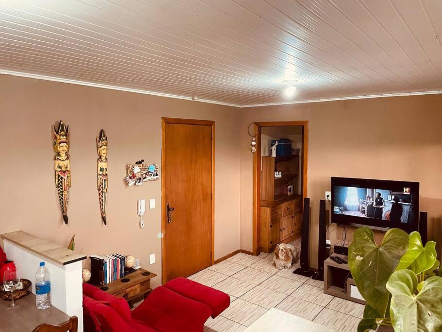 een woonkamer met een rode bank en een flatscreen-tv bij Apartamento em ótima localização in Canela