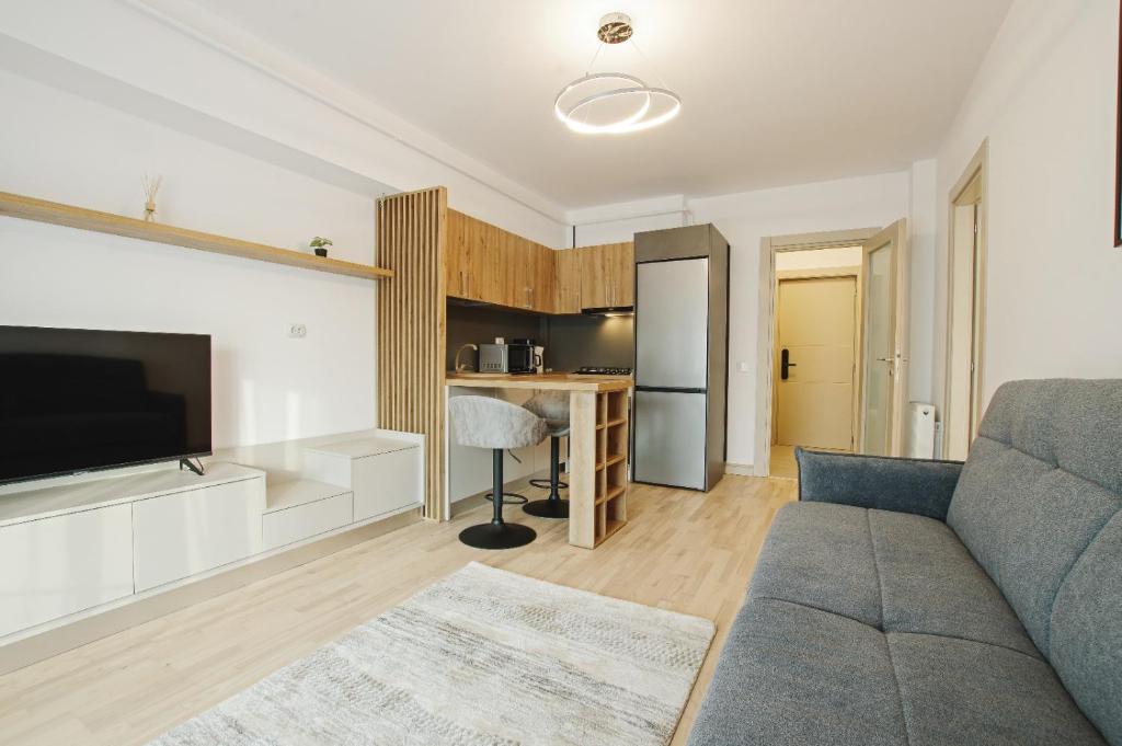 a living room with a couch and a kitchen at Himson-Beige Apartment in Iaşi