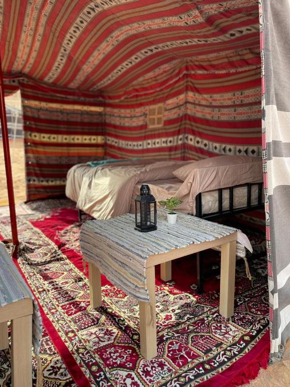 a room with a table and a bed in a tent at Authentic Desert Camp - Al Wasil 