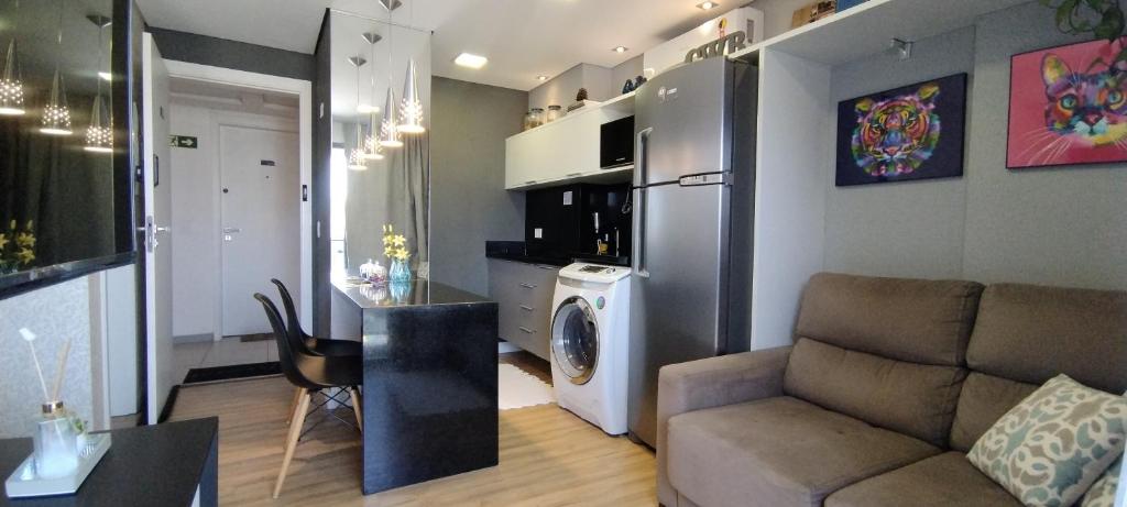 een woonkamer met een bank, een wasmachine en een droger bij Excelente Studio Completo Centro Curitiba - Ar Condicionado - 7th Avenue in Curitiba