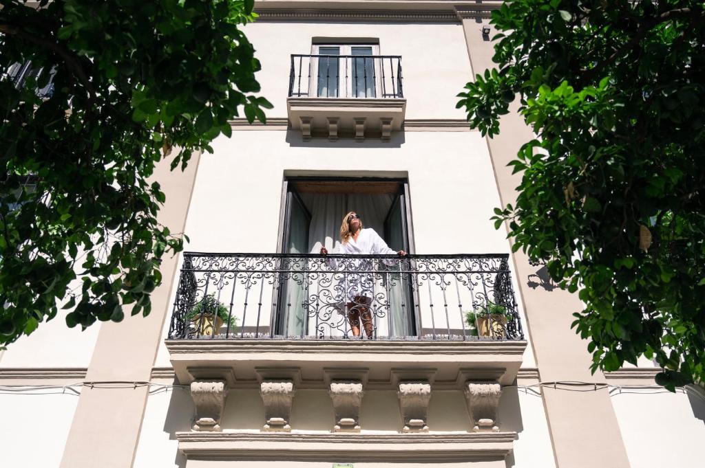 a woman standing on the balcony of a building at Legado Magdalena Hotel in Seville