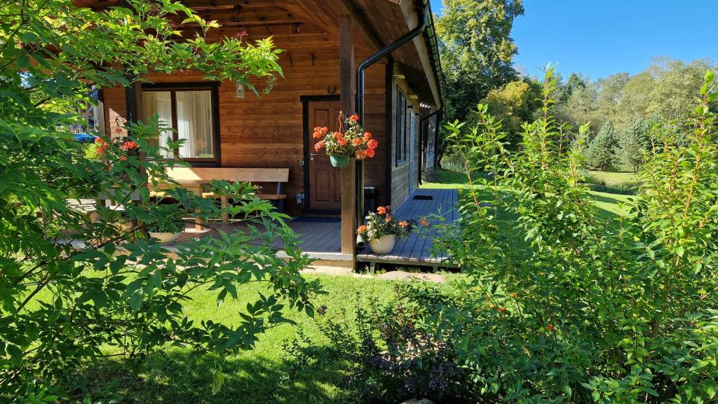 una cabina in legno con portico, panca e fiori di Atostogų namelis-pirtis Prie upės a Anykščiai
