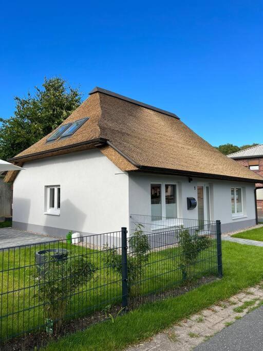 a white house with a brown roof and a fence at Modernes Ferienhaus im Eidertal in Delve