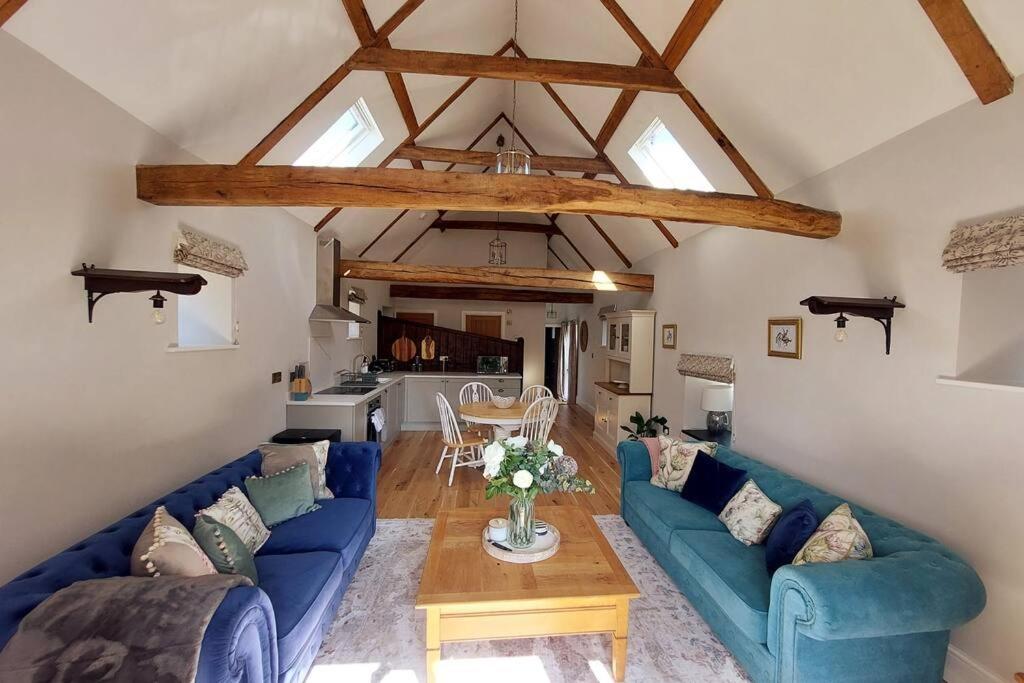 a living room with blue couches and a table at Luxury Victorian Hayloft barn self contained in South Witham