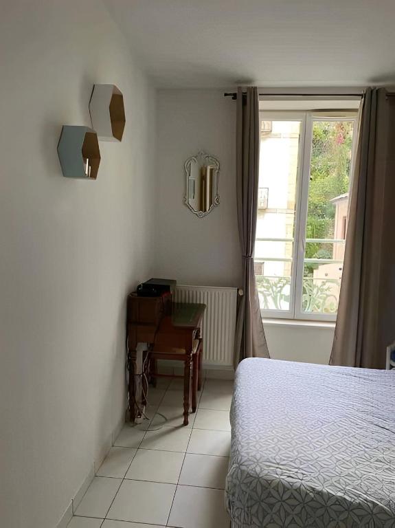 a bedroom with a bed and a desk and a window at Un moment de Détente au cœur de Vals-les-Bains in Vals-les-Bains