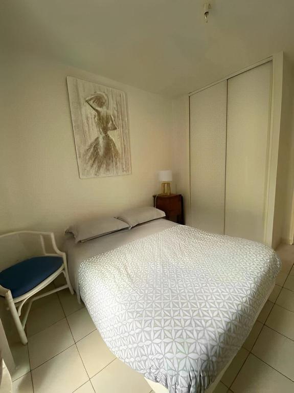 a bedroom with a white bed and a chair at Un moment de Détente au cœur de Vals-les-Bains in Vals-les-Bains