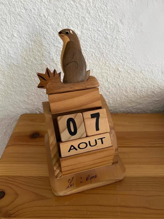 a bird sitting on top of a wooden clock at Un moment de Détente au cœur de Vals-les-Bains in Vals-les-Bains