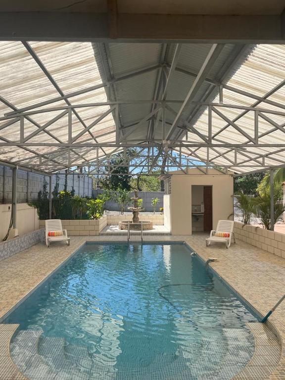 a large swimming pool in a building with a roof at Casa Atardecer Turrubares 