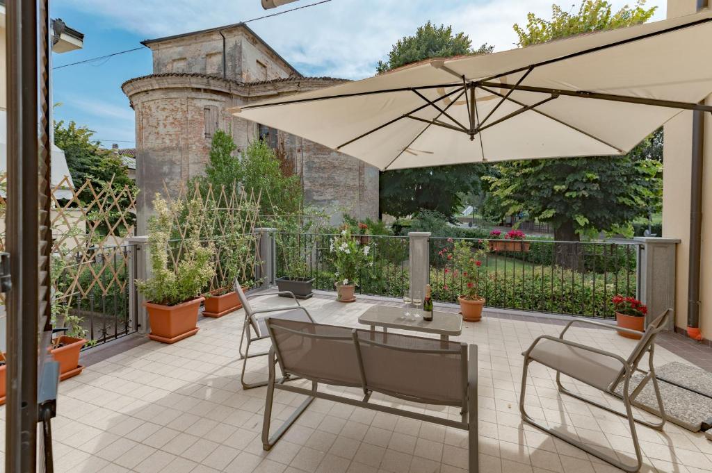 patio ze stołem, krzesłami i parasolem w obiekcie Il Nido sul Po w mieście Casalmaggiore