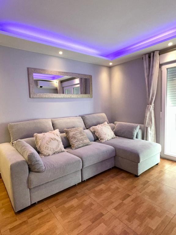 ein Wohnzimmer mit einem Sofa mit violetten Lichtern in der Unterkunft Apartamento Zaragoza Picarral in Saragossa