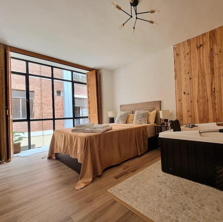 Un dormitorio con dos camas y una gran ventana. en Vivienda Plaza Mayor, en León