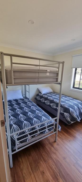 a bedroom with two bunk beds and a wooden floor at Wedderburn Caravan Park in Wedderburn