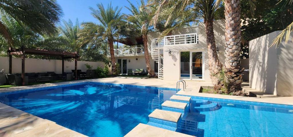 a swimming pool in front of a house with palm trees at فيلا مسقط - Muscat Villa in Bawshar