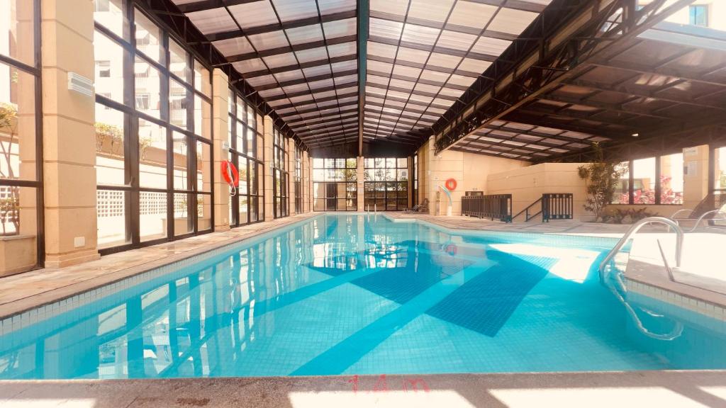 a large swimming pool with blue water in a building at Suítes Inside Hotel Pinheiros in Sao Paulo