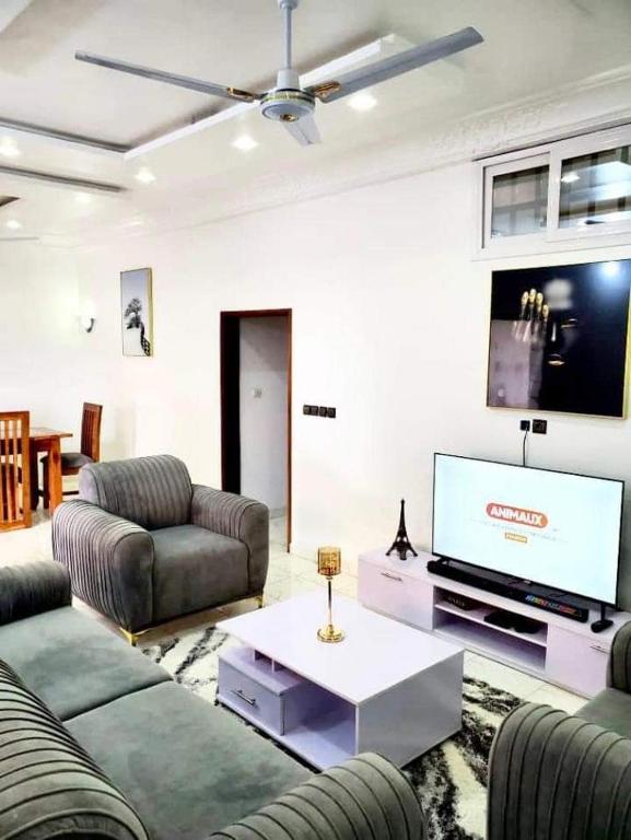 uma sala de estar com sofás e uma televisão de ecrã plano em Agimlog em Allada