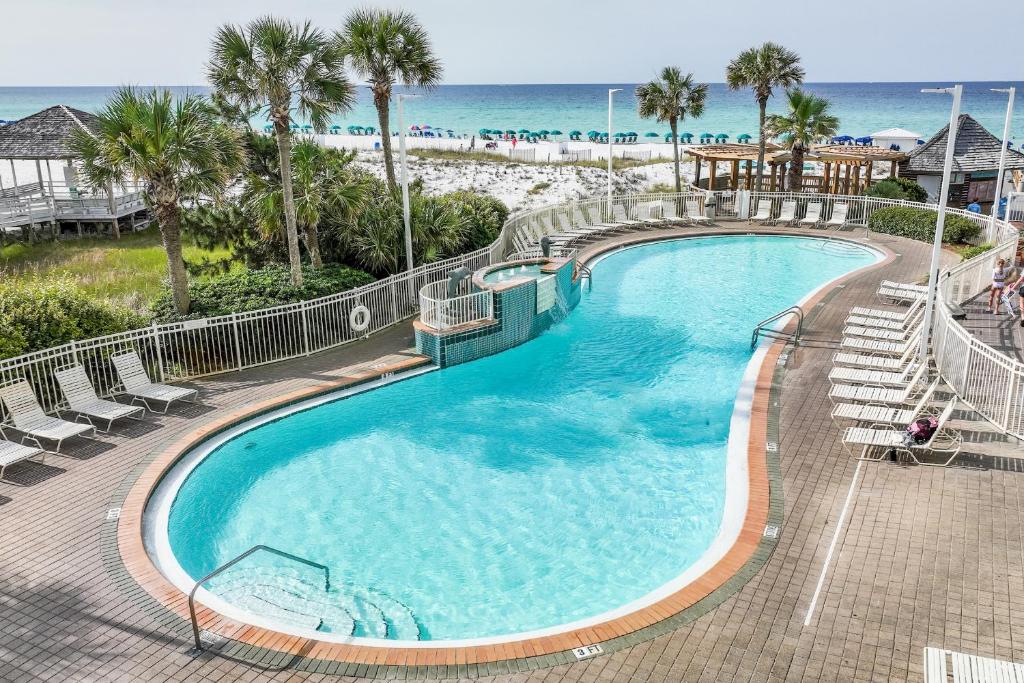ein großer Pool mit Stühlen und der Strand in der Unterkunft Pelican Beach Resort by Colasan in Destin