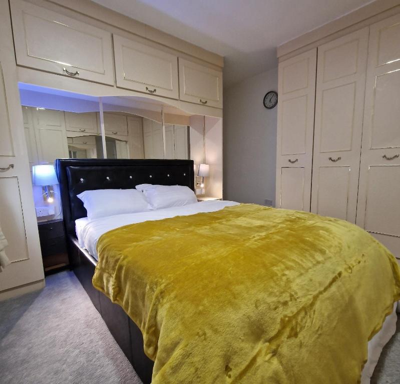 a bedroom with a large bed with a yellow blanket at Delightfully & Spacious Guest House in Farnworth in Farnworth