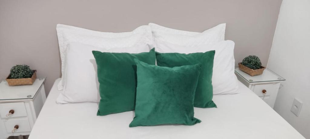 - un lit avec des oreillers blancs et des oreillers verts dans l'établissement Loft Ymará Arraial, à Arraial do Cabo