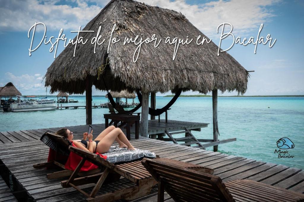 a woman laying in a beach chair on a dock at Caba&ntilde;as Hostal & Camping Magic Bacalar in Bacalar