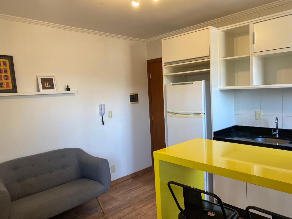 a kitchen with a yellow counter top and a couch at Studio Minimalista Região Central Residencial Padre Kolb 201C in Joinville