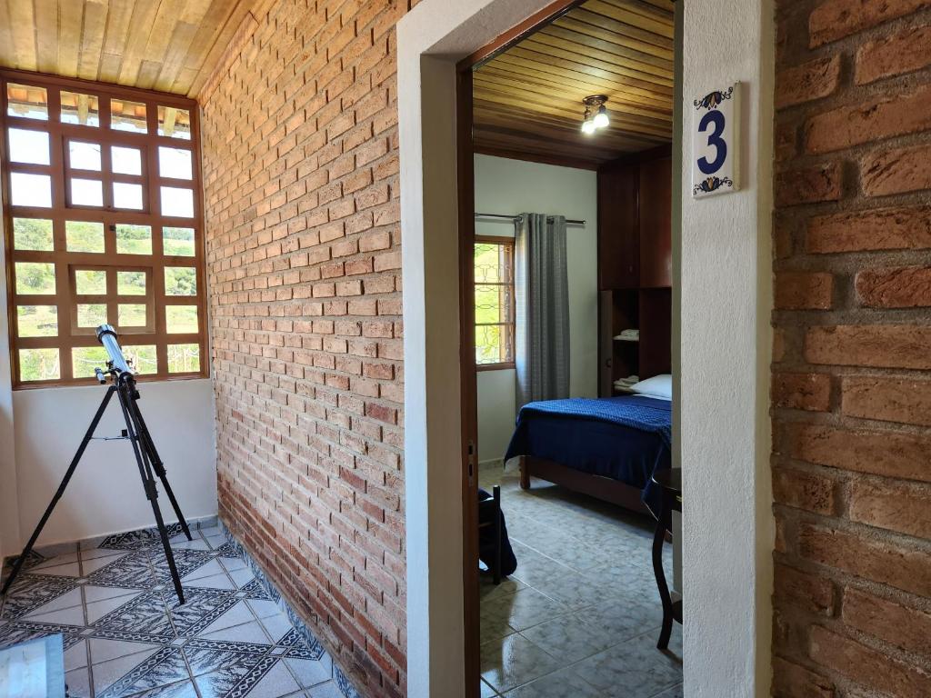 Zimmer mit Ziegelwand und Schlafzimmer in der Unterkunft Pousada Pedacinho do ceu suite Izah in Cunha