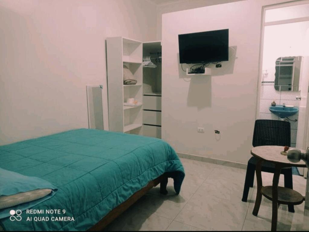 1 dormitorio con 1 cama, TV y mesa en Angello, en Lima