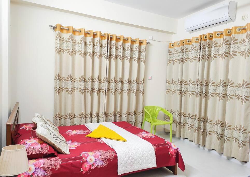 sypialnia z czerwonym łóżkiem i zielonym krzesłem w obiekcie Sweet & affordable stay in Dhaka w mieście Dhaka