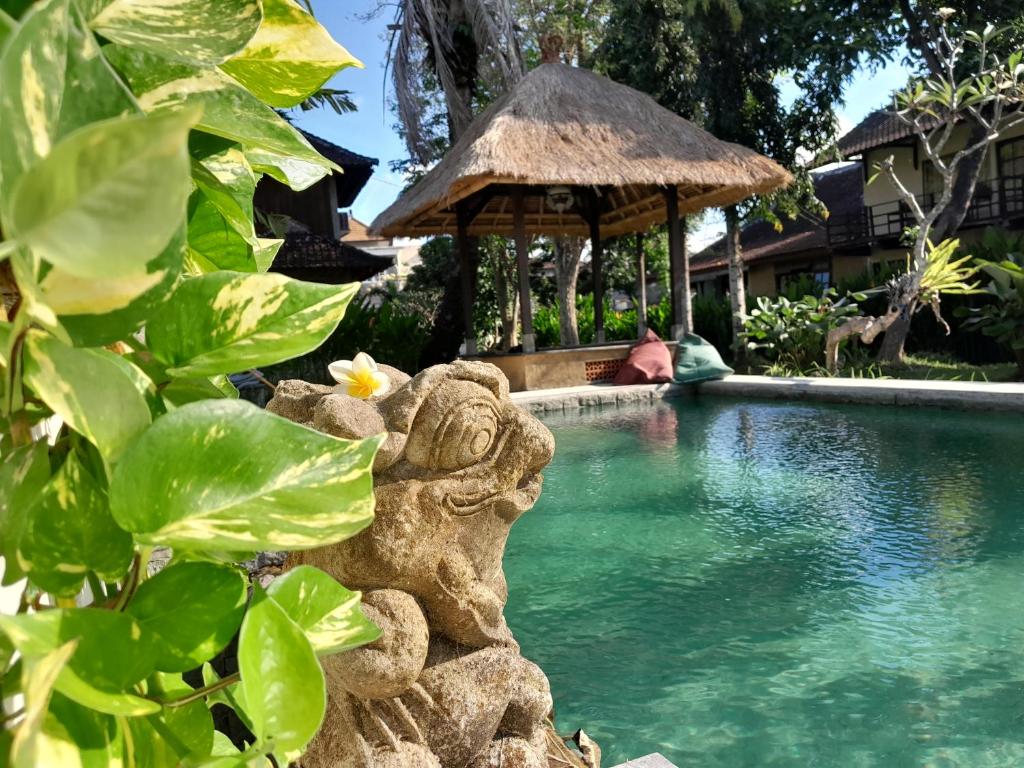 a resort swimming pool with a statue next to a building at Puri Kutat Lestari in Sanur