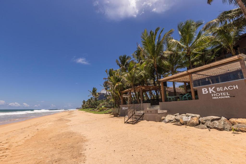 a building on a beach with palm trees and the ocean at BK Beach Boutique Hotel - Hikkaduwa in Hikkaduwa