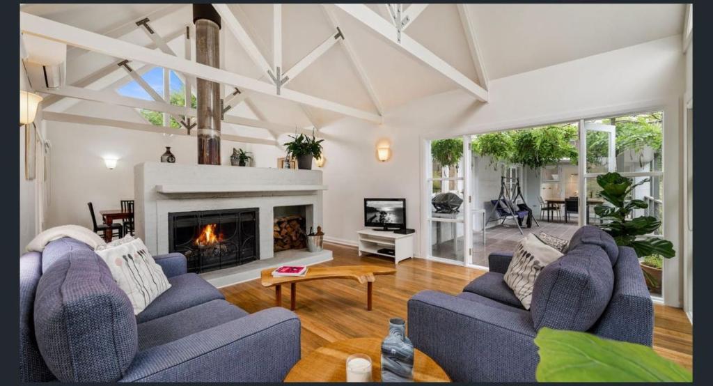 sala de estar con 2 sofás azules y chimenea en Jamieson Cottage, en Wentworth Falls