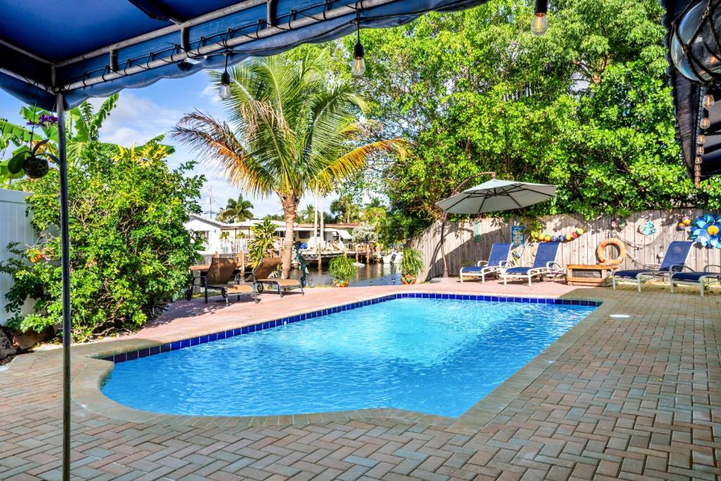 a swimming pool with chairs and an umbrella at Purely Pompano, Pool, Water front, Paddleboard, Beach, 5 bedroom 3 bath in Pompano Beach