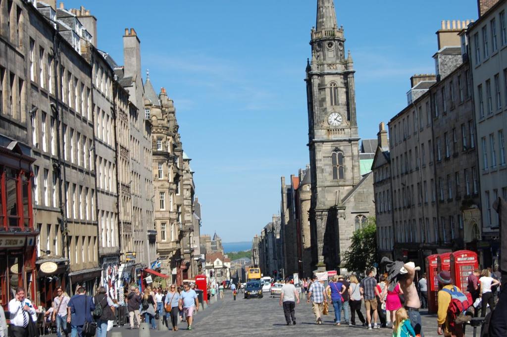 una multitud de personas caminando por una calle con una torre de reloj en Royal Mile Cranston, en Edimburgo