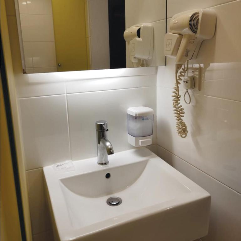 w łazience znajduje się umywalka, suszarka do włosów i telefon. w obiekcie Room in Genting Highland w mieście Genting Highlands