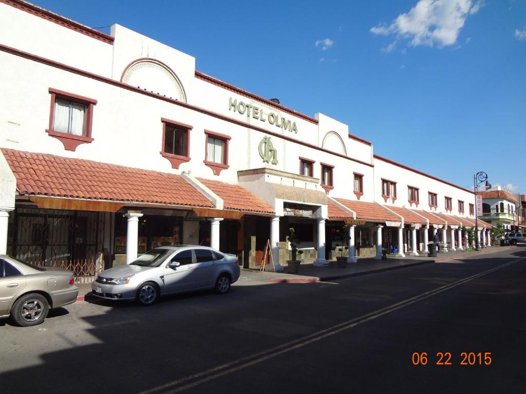 a street with cars parked in front of a building at Hotel Olivia in Nogales