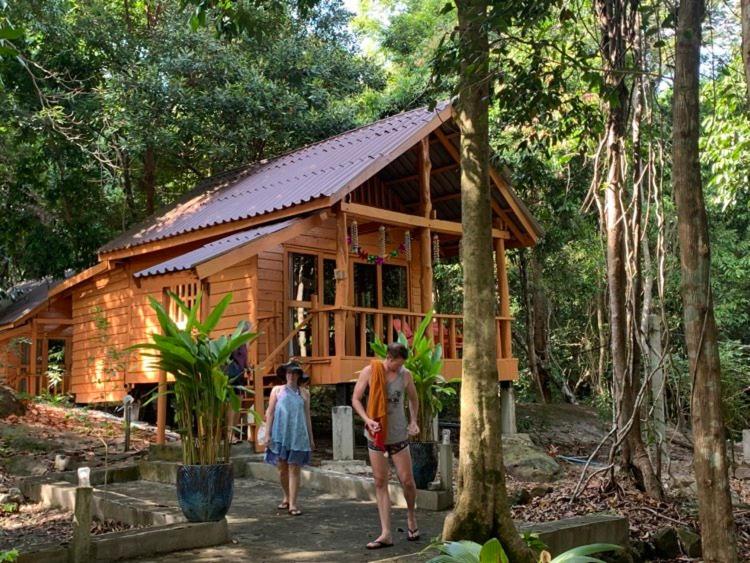 a group of people standing in front of a wooden cabin at The Wavy Sailor Bungalow's in Koh Rong Island