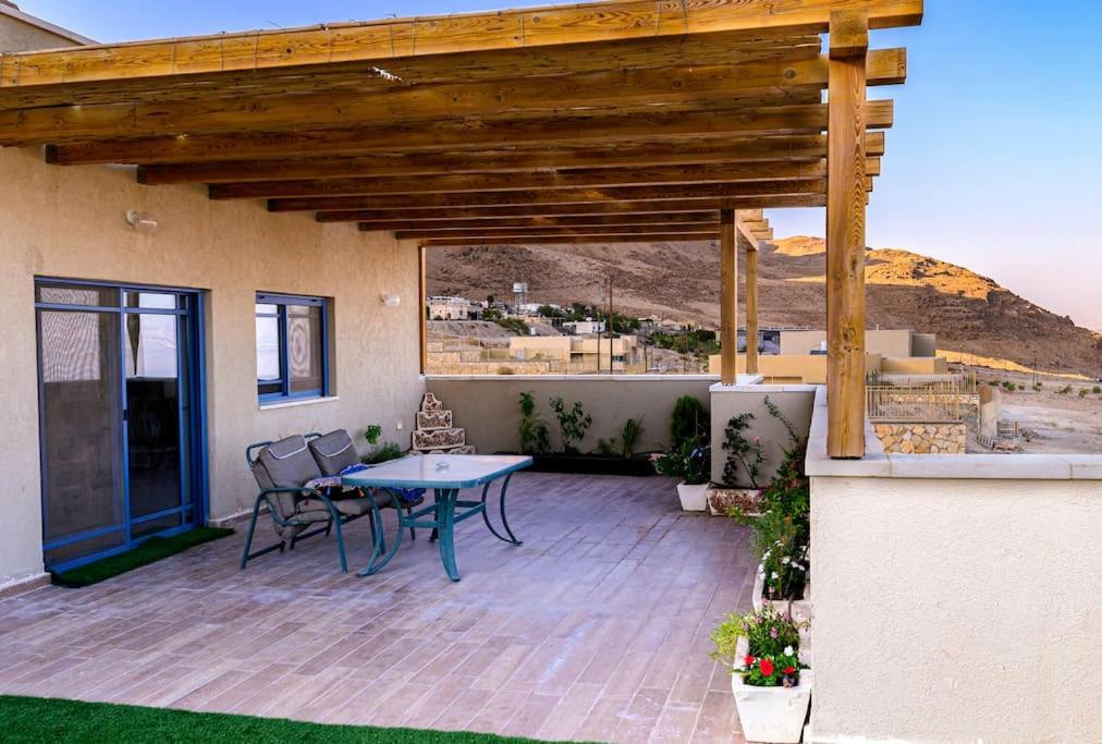 a patio with a table and chairs on a house at Magnificent dead-sea view in Ovnat