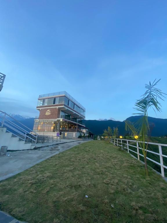 een gebouw met een hek voor een veld bij Dhikidada Resort in Pokhara