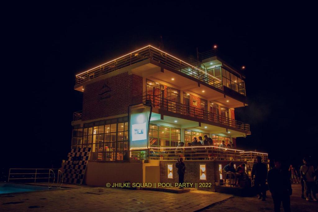 un edificio con gente de pie delante de él por la noche en Dhikidada Resort en Pokhara