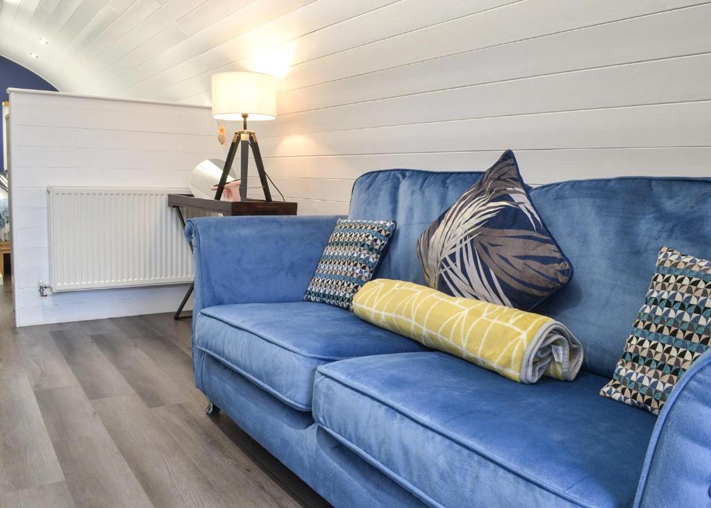 a blue couch with pillows on it in a living room at Peacock Lake Glamping in East Bridgford